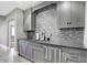Close-up of the gray wet bar with stone countertops and stainless dishwasher at 3582 Pete Dye Blvd, Carmel, IN 46033