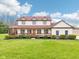 Stunning two-story home with a red roof and inviting wraparound porch, surrounded by lush greenery at 4339 W Briarwood Rd, Monrovia, IN 46157