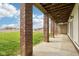 Covered lower-level patio with brick columns, concrete floors, and a partially fenced in yard with an open view at 4339 W Briarwood Rd, Monrovia, IN 46157