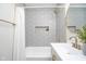 Nicely decorated bathroom featuring gray tile, a bathtub, and a modern vanity with gold finishes at 4719 Evanston Ave, Indianapolis, IN 46205