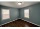 Comfortable bedroom with wood-look floors, two windows, and calming teal-colored walls at 4823 Atwell Dr, Lawrence, IN 46226
