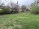 A spacious, grassy backyard featuring mature trees and a trampoline, offering ample space for outdoor activities and relaxation at 5240 Regency Dr, Columbus, IN 47203