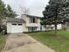Classic home with attached garage, spacious driveway, and mature trees on a lush lawn at 6225 Roberts Creek Ln, Indianapolis, IN 46221