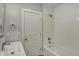Bright bathroom featuring a tub with tile surround and modern fixtures and a white door at 715 Cottage Ave, Indianapolis, IN 46203