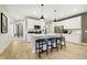 Open-concept kitchen with a large island, pendant lighting, white cabinets, stainless appliances, and bar stool seating at 7342 Shroyer Way, Noblesville, IN 46062