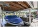 Covered boat dock with lift and lakeside patio featuring wicker furniture on a calm lake with neighborhood homes in the background at 7668 Heather Dr, Nineveh, IN 46164