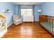Cozy Bedroom with wood floors, ample light, an accent chair, and a comfortable crib at 7811 Hoover Rd, Indianapolis, IN 46260