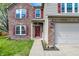Inviting front entrance with brick accents, updated exterior lighting, a welcome mat, and attached two car garage at 8531 Aberdeenshire Ct, Indianapolis, IN 46259