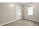 A bedroom featuring wood-look floors, tan walls, a window, and a white door at 8560 N College Ave, Indianapolis, IN 46240