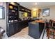 Basement bar features dark cabinetry, a mirrored backsplash, and a countertop bar at 9789 Logan Ln, Fishers, IN 46037