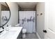 Neutral bathroom features a modern vanity, oval mirror, and shower with a unique 