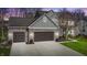 View of the two car garage featuring brick and siding, a well-kept lawn, and professional landscaping at 9789 Logan Ln, Fishers, IN 46037