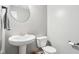 Stylish powder room featuring pedestal sink, round mirror, and modern fixtures at 9916 Gallop Ln, Fishers, IN 46040
