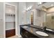 Bathroom featuring double sinks, granite countertop, a large mirror, a walk-in shower, and walk-in closet at 1 Virginia Ave # 707, Indianapolis, IN 46204