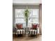 Cozy seating area featuring striped chairs, decorative pillows, and a hanging spider plant in front of a bright window at 10220 Tournon Dr, Fishers, IN 46037