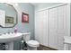 Clean, powder-blue bathroom featuring a pedestal sink, toilet, and a sizable closet for storage at 10533 Williamsburg Dr, Newburgh, IN 47630