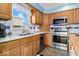 Well-lit kitchen features stainless appliances, wood cabinets, tile backsplash, and a view to the backyard at 10533 Williamsburg Dr, Newburgh, IN 47630