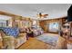 Living room featuring wood paneling, hardwood floors, a ceiling fan, and cozy seating at 11015 S State Road 58, Columbus, IN 47201