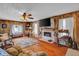 Cozy living room featuring wood paneling, fireplace, hardwood floors, and a ceiling fan at 11015 S State Road 58, Columbus, IN 47201