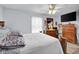 Light filled bedroom with hardwood floors, ceiling fan, dresser, and large bed at 11015 S State Road 58, Columbus, IN 47201