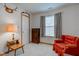 Bright bedroom featuring a window with curtains, a dresser, and a comfortable red armchair at 118 Presidential Ct, Greenfield, IN 46140