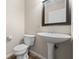 Cozy half-bathroom with a pedestal sink, toilet, and framed mirror at 14953 Lovely Dove Ln, Noblesville, IN 46060