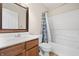 Cozy bathroom features a tub and shower combo with patterned curtain, wood vanity, and framed mirror at 14953 Lovely Dove Ln, Noblesville, IN 46060