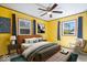 A bedroom with yellow walls, two windows, ceiling fan, and dark blue curtains at 1933 Ruth Dr, Indianapolis, IN 46240