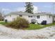Backyard view of white house with gravel and grass, leading to an entrance with small deck and shrubbery at 217 S 17Th Ave, Beech Grove, IN 46107