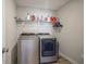 Functional laundry room showcasing a modern washer and dryer set with a shelf, and clothing hangers at 2237 S Copperstone Dr, New Palestine, IN 46163
