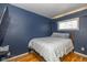 Cozy bedroom with blue walls, wood floors, and a comfortable bed under a window at 2416 Depauw Rd, Indianapolis, IN 46227