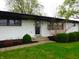 Charming single-story home featuring a painted brick exterior, complemented by dark accents and manicured landscaping at 2416 Depauw Rd, Indianapolis, IN 46227