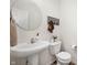 Clean and simple half bathroom with a pedestal sink, round mirror, and modern fixtures at 2681 Pumpkin Patch Ln, Indianapolis, IN 46229