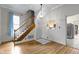 View of the wood staircase, chandelier, and pass-through to the kitchen in this bright living room with hardwood floors at 304 W 4Th St, Greenfield, IN 46140