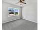 A bright bedroom with carpet, a modern ceiling fan, and a large window offering neighborhood views at 3278 Jasper Ln, Brownsburg, IN 46112