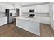 Modern kitchen with white cabinets, a large island, stainless steel appliances, and hardwood floors at 3278 Jasper Ln, Brownsburg, IN 46112
