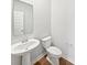 Half-bathroom with pedestal sink, toilet, modern mirror and hardwood floors at 3278 Jasper Ln, Brownsburg, IN 46112
