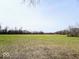 A serene open field, partially covered in grass, with a backdrop of tall, bare trees and a clear sky at 3559 N Us Highway 41, Bloomingdale, IN 47832