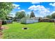 Large backyard featuring a well-manicured lawn with a fire pit and a detached garage at 3809 Wildwood Dr, Indianapolis, IN 46239