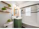 Charming bathroom with green vanity, floating shelves, and a subway tiled shower and bathtub at 4102 N Illinois St, Indianapolis, IN 46208