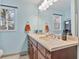 Bathroom with double sink vanity, large mirror, and window overlooking a wooded backyard at 4159 Asbury St, Indianapolis, IN 46227