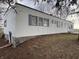 A manufactured home with white siding, gray shutters, and a walkout basement entrance; mature trees frame the property at 4653 E Us Highway 36, Markleville, IN 46056