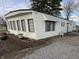 Exterior view of a manufactured home with white siding, a small patio area, and landscaping features at 4653 E Us Highway 36, Markleville, IN 46056