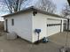 Exterior view of a white detached garage with a roll-up door, a mailbox, and various outdoor decorations at 4653 E Us Highway 36, Markleville, IN 46056