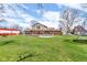 Large grassy backyard showcasing a charming brick home, storage barn, and recreational trampoline at 4930 Founders Ct, Anderson, IN 46017