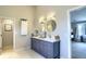 Bathroom with double sink vanity, round mirrors, gray cabinets and decorative white and gray tiled floor at 4932 Willow Ridge Ct, Zionsville, IN 46077