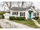 Charming home featuring a bright teal front door, landscaped yard, and detached garage at 5140 Indianola Ave, Indianapolis, IN 46205