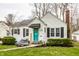 Charming home featuring a bright teal front door, landscaped yard, and cozy seating area on the front porch at 5140 Indianola Ave, Indianapolis, IN 46205