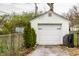 Exterior view of detached garage with a white door and fresh green trees at 5140 Indianola Ave, Indianapolis, IN 46205