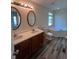 Bright bathroom featuring double sinks with wooden vanity, tub, and modern gray vinyl flooring at 563 Jet Stream Blvd, Westfield, IN 46074